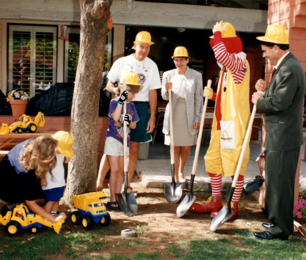 Ronald McDonald, 4 adults, and 2 children stand in hard hats and shovels.