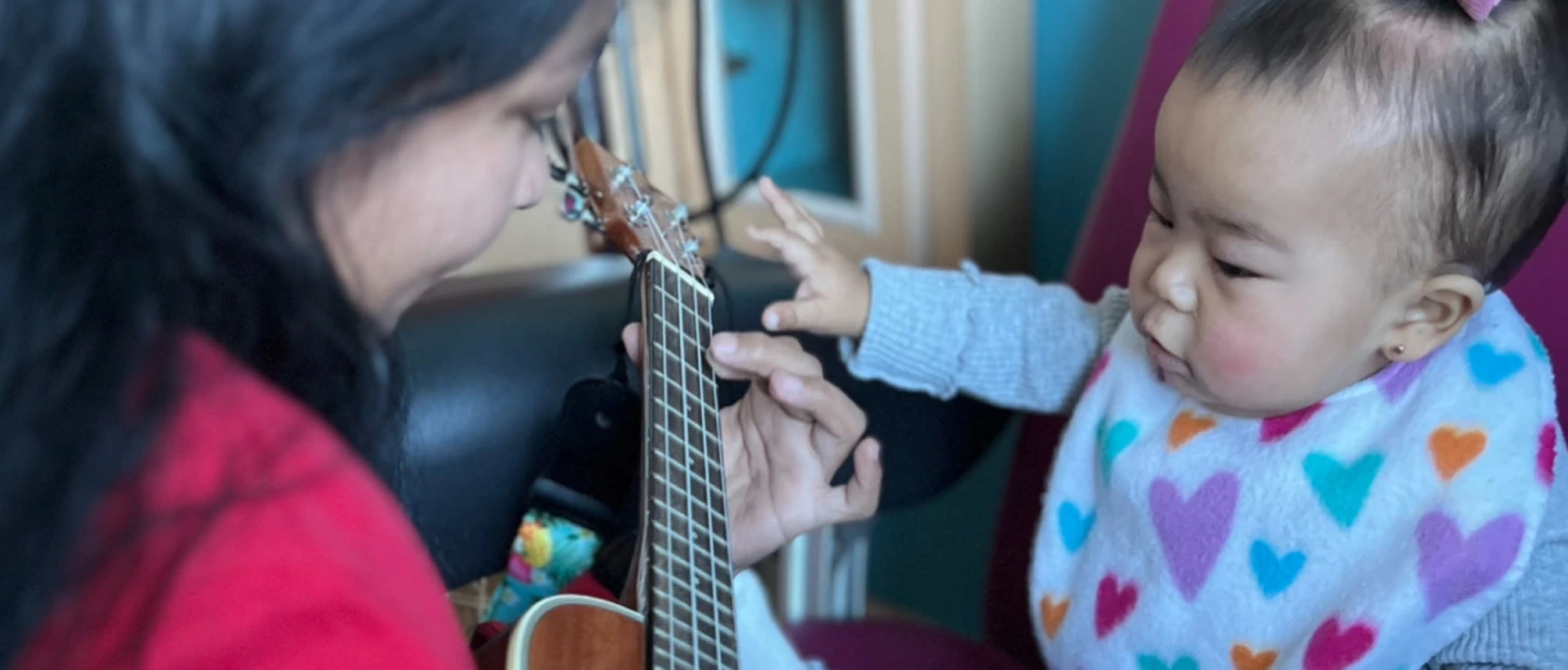 musician playing ukulele with young child