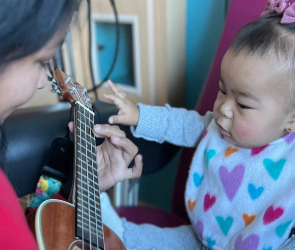 musician playing ukulele with young child