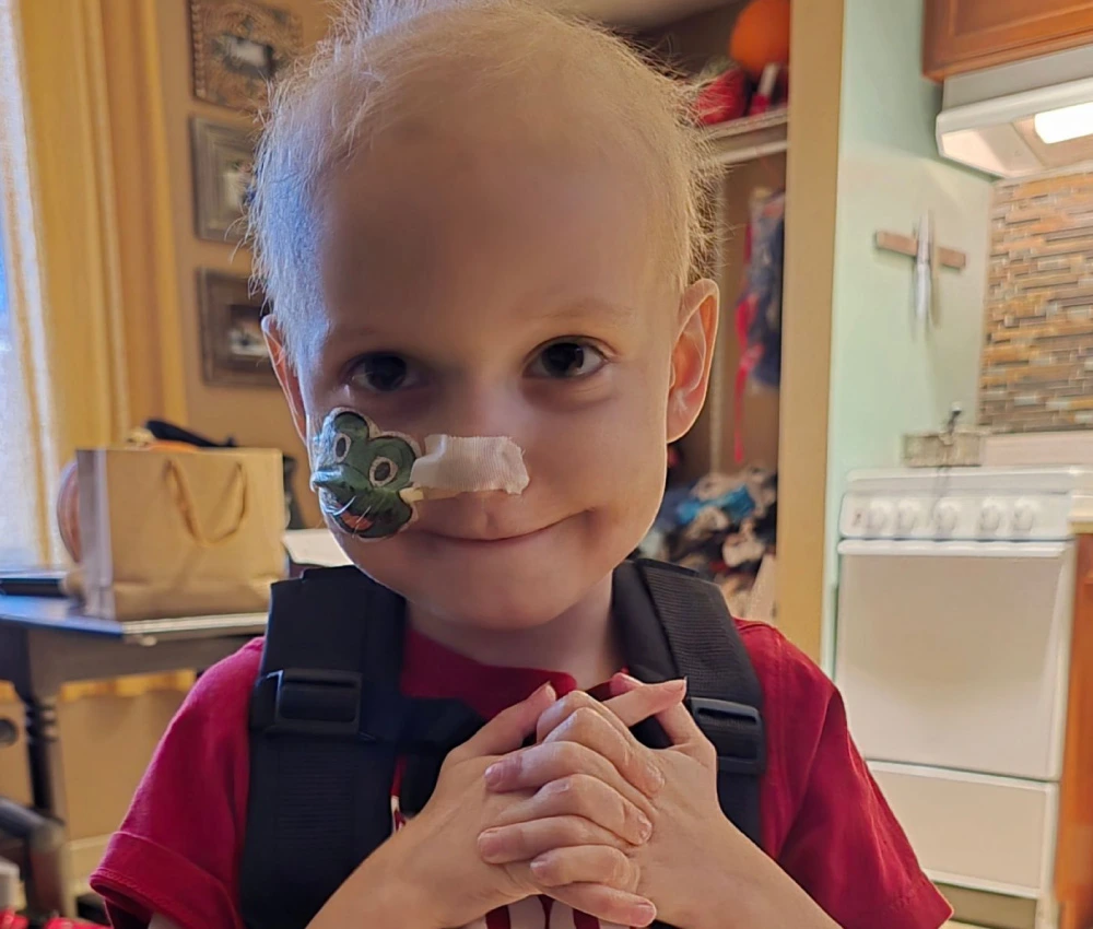 young boy Remington smiling with hands clasped on his chest