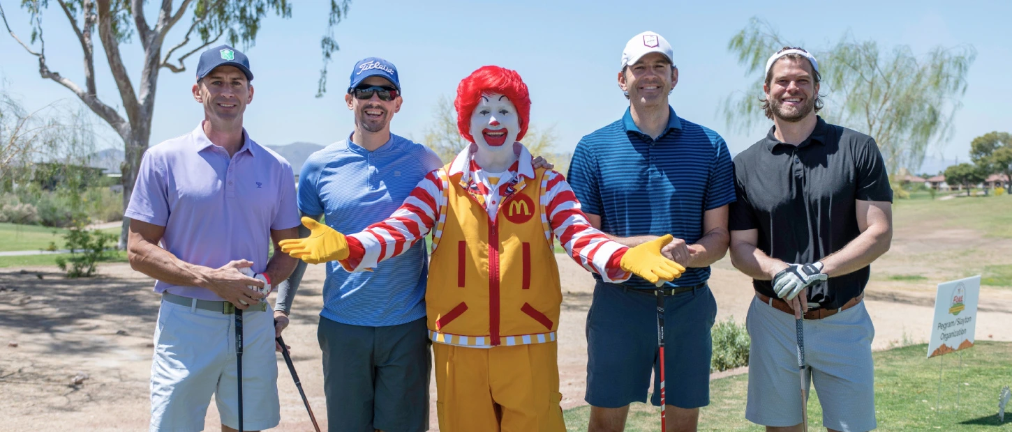 group of golfers with Ronald McDonald in the middle for a group photo