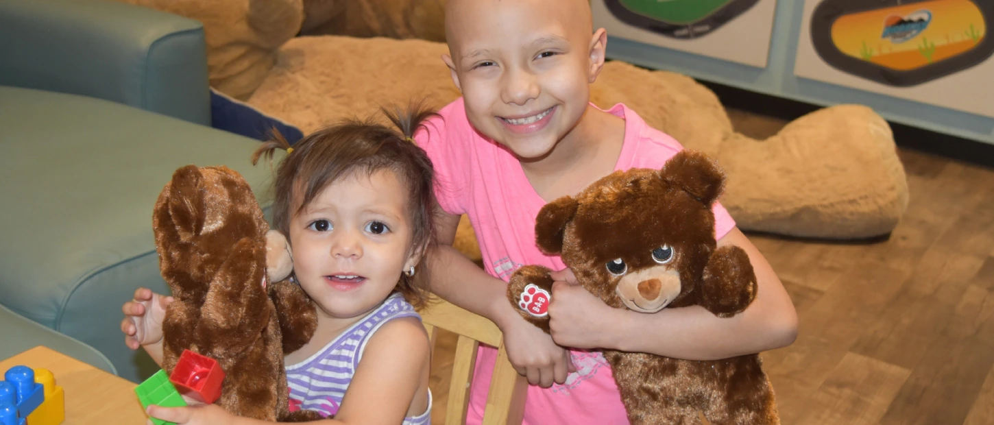 two young girls playing together in playroom with stuffed animals