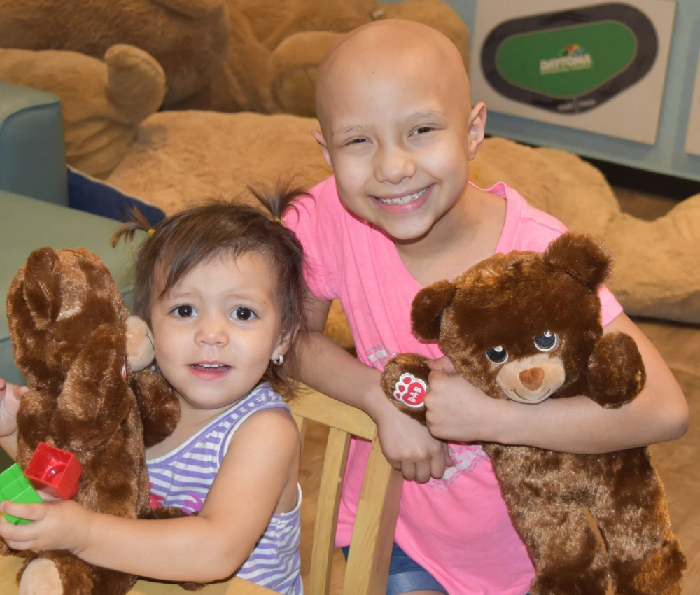 two young girls playing together in playroom with stuffed animals
