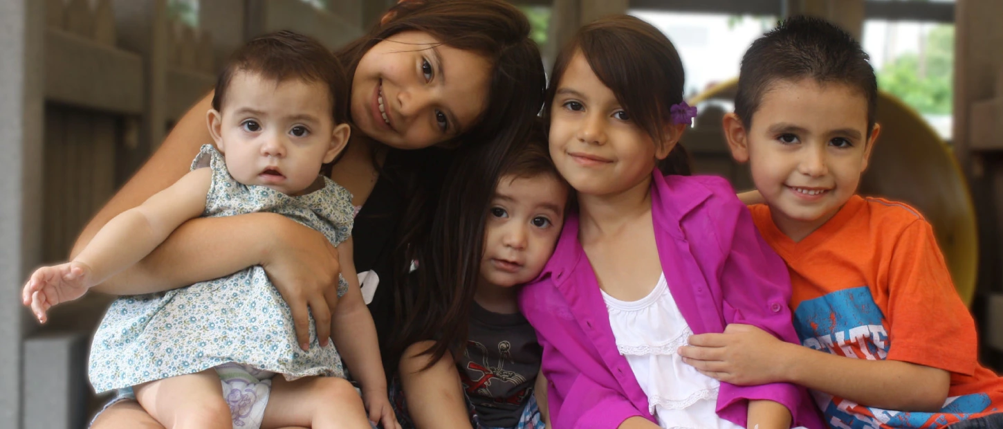 Family of five young siblings gathered closely together for family photo