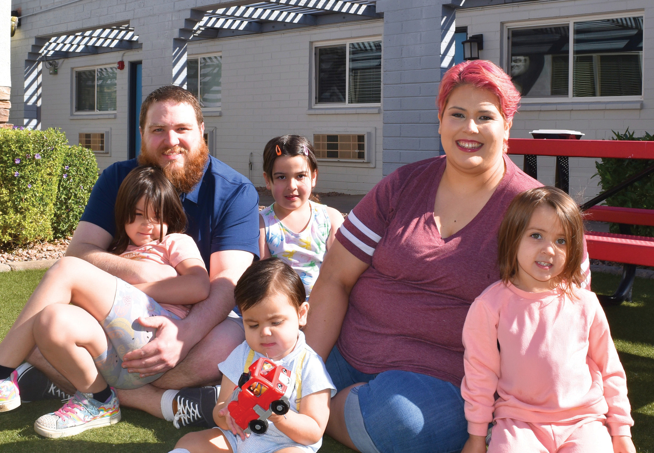 family of six sitting on lawn in front of RMH Central & Northern Arizona